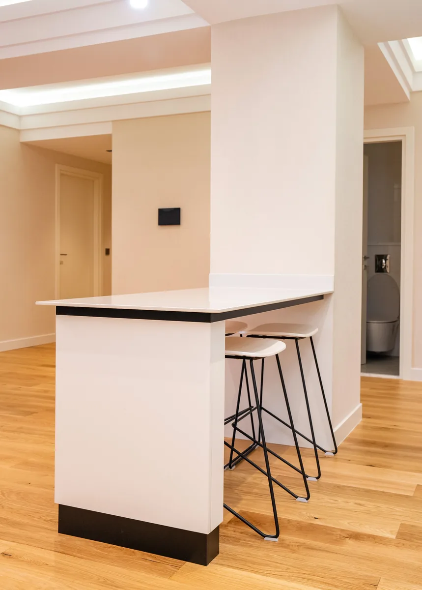 Contemporary kitchen space features sleek bar, hardwood flooring